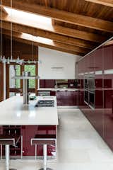 The modern kitchen with glossy, red cabinets is spacious with ample storage and a center island with seating.&nbsp;