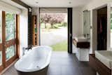 The ensuite master bath features a freestanding tub, and more floor-to-ceiling glazing affords lush views across the gardens.&nbsp;