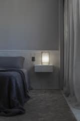 The brass bedside lamp with a silk lampshade designed by Alan sits on a marble and ash wood floating nightstand.