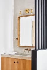 The bathroom vanity features a concrete counter from 1025 Studio, a mirror from Kenneth Miller, and lighting by&nbsp;Noevara.