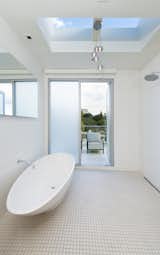 The highlight of the master bathroom suite is the oval-shaped soaking tub with a skylight above. A sliding door leads out to a terrace.
