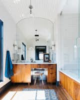 The master bathroom features a coved tile ceiling, a custom walnut vanity, and a large soaking tub. 