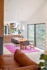 A peninsula with hidden storage serves as a divider between the kitchen and the dining room. Two Caravaggio Pendants by Fritz Hansen hangs over the dining table. The sectional sofa is a vintage find.&nbsp;