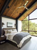 The master bedroom has a Restoration Hardware bed, wall sconces from Designer Metal Works, and a wall of windows.&nbsp;&nbsp;