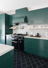 The cabinets were custom designed by&nbsp;Síol Studios&nbsp;and painted Deep Jungle—a bold shade of green from Pratt &amp; Lambert. The backsplash features hand-painted terra cotta tiles by Walker Zanger. The oven range is from AGA Countertops. The floor is finished with hand-painted arabesque terra cotta tiles from Tabarka Studios.
