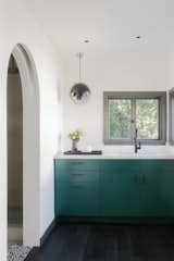 The kitchenette picks up the same green cabinetry as the kitchen in the main house. The pendant lighting is by Louis Weisdorf for Gubi.