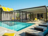 The pool area features a shaded section with original Italian patio furniture in yellow.