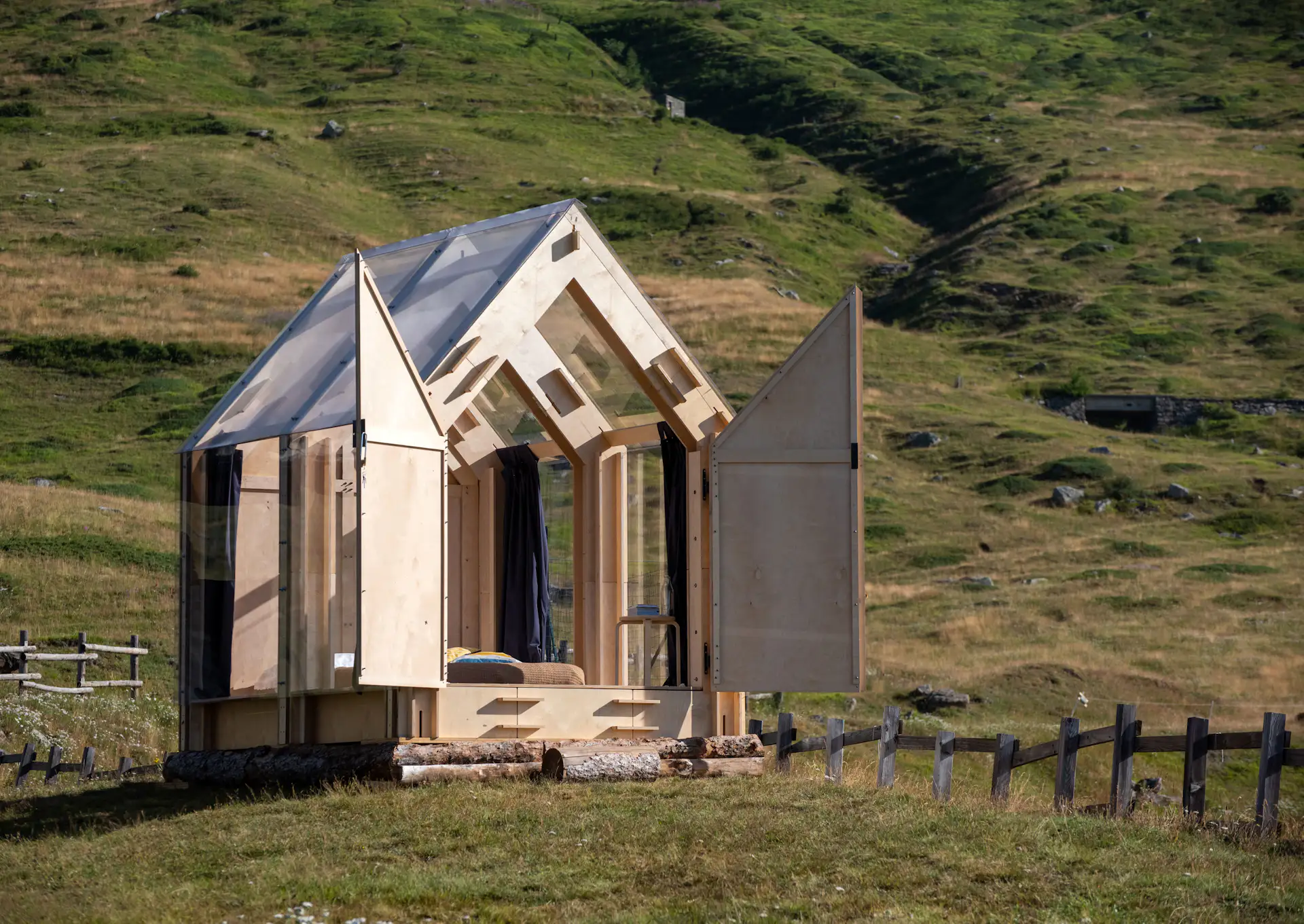 Birch plywood panels, full-height windows, and a transparent roof compose "Immerso Glamping" set in the Italian alpine town of Usseaux.