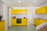 Gerlier chose to recycle the original Ikea kitchen by simply repainting the laminate fronts bright yellow and adding a wood countertop. The sunny shade was chosen to brighten the space and "add cheerfulness to a sometimes very dark room".