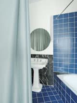 The bathroom is tiled a bold blue, with repurposed Nero Marquina marble which was originally part of the kitchen flooring.