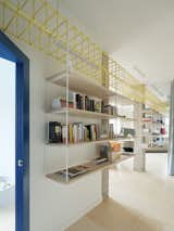 The bookcase is suspended from a bright yellow structural frame that runs the length of the apartment and down the hallway.&nbsp;