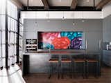 Síol Studios designed the custom lighting system and walnut-and-steel kitchen island, which was fabricated by Trojan Woodworking. A vibrant mural by Bay Area artist Jet Martinez enlivens the space, and the bar stools are from Ohio Design. 