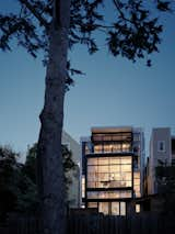 The glass-backed home illuminated at night. 