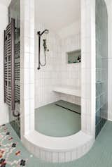The elegantly curved shape of the open shower in the master bathroom came from the couple's desire to not have to deal with cleaning a glass door or having a curtain. The opening also allows some natural light to enter the shower. The vertically-positioned rectangular tiles are from Portland company Clayhaus Modern Tile.