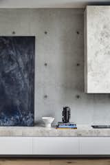 In addition to outfitting the home with furnishings, Kennon also selected the artwork. Here, a painting by New Zealand artist Matt Arbuckle rests on a low built-in storage cabinet clad in Tundra Mist Natural Stone, a material that provides texture against the tonally similar concrete walls.