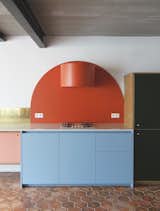 The kitchen, which is meant "not to look like a kitchen" is composed of art deco-inspired shapes, such as this bold, red circular form that Otten created to wrap an ordinary range hood. Even the oven is hidden behind the custom cabinets. 