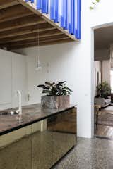 "The planter box was an excuse and a solution to integrate the electric plugs on the counter," shared Otten. The stunning slab of pink marble which serves as the island's countertop is the result of a trade between the client, an artist, who traded a work of art for it with the art-collecting owner of Vandeweghe, the marble company, where the beautiful slab of pink marble is from. Brass cabinet doors reflect the terrazzo flooring from Bomarbre.&nbsp;