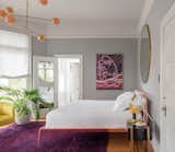 The master bedroom was painted a soothing shade of pale gray with white ceilings and doors. Peach, fuchsia, and purple tones create a dynamic contrast in the form of a vintage, overdyed rug from Rug Knots and a painting by Amelia Midori Miller. The Urbino bed in copper is from Property Pendant, and the Line Pendant 06 light is from Douglas and Bec. 