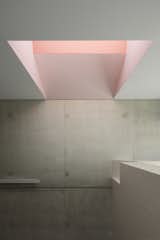 A pink-hued skylight and reading nook animate the in-situ concrete stair wall.