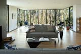 The living room extends out into the forest into a sitting area that is wrapped with full-height windows. This space could also be used as an additional dining area.&nbsp;