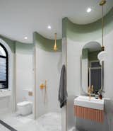 The spacious main bathroom (a former bedroom), joins marble, brass, and green elements. It is innovative for its use of "micro-spaces" that are subdivided and contained within the scalloping of the rear wall. They are meant to make each element feel special and separate, dividing a large room into smaller spaces that "hug you as you use them."