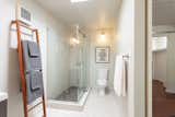 The updated main bathroom has a glass-enclosed shower, a double vanity, and a skylight.