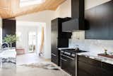 The kitchen features custom black wood cabinetry, Italian porcelain counters, and a black plaster hood above an Aga Mercury range.
