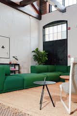 Suite names like Heddle, Twill, and Weft reference the building’s past. The kelly-green couch is by Muuto.&nbsp;