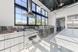 The industrial kitchen features a gigantic island topped with Carrera marble.