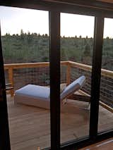 Opening glass NanaWall system, lounge chair, forest view