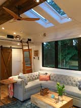 Automatic skylights, reclaimed wood beam, Chesterfield sofa, blue rug, barn door, fan, and Dutch door