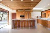 Natural wood accents and opposing NanaWall folding glass walls elevate the biophilic design of this Hawaii kitchen. The folding window to the left converts the space into an open bar perfect for entertaining guests or al fresco dining.