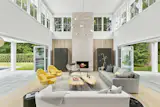 This Farmhouse modern East Hampton home takes design inspiration from contemporary styles within its open concept lounge area. Walls completely vanish with the help of two wood clad NanaWall folding glass systems—taking indoor/outdoor living to the next level with biophilic design.