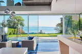 Nautical modern design is complemented by picture-like views in this waterfront residence. Floor-to-ceiling NanaWall minimal sliding glass wall panels frame the extensive backyard and open up the tranquil living area to fresh air and greenery.