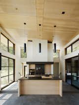 Kitchen, Pendant Lighting, Range, Wood Cabinet, Wood Backsplashe, Concrete Floor, and Undermount Sink Warm wood and dark surfaces contrast with white walls.  Photo 5 of 10 in Four Enormous Glass Doors Turn This Northern California Home Into an Outdoor Pavilion from Gallery