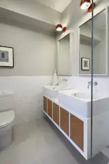 A photo of the double vanity in the children's bathroom.  The vanity was custom made from Corian with Scola sinks from Duravit and one of our favorite faucets from Vola designed by Arne Jacobsen.  The inset panels are natural cork with a wax finish.