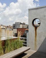 The garden is accessed from a rooftop penthouse designed by pulltab and built two years earlier.  A large diameter steel pipe was cut and placed into a new stucco wall.  This aperture frames a view to a power plant located on the Lower East Side.  The steel ring was left unpainted so it can rust and bleed down the wall.   The floating bench is made from Cor-Ten steel and teak which is left to weather a beautiful grey.