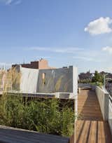 A view from the entry to the roof deck toward the outdoor shower.  The shower wall has an opening which frames the New York Life Insurance Building which can be seen in the distance.