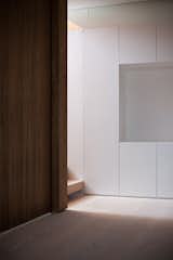 A high-level mirror—above the line of vision of a viewer—doubles the perceived size of the space, while also reflecting natural light from the open-rise staircase and the adjacent frameless glazing on the level above.