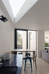 Oblique views of the garden from the kitchen are framed through rectilinear apertures to the dining and living zones of the new space.
