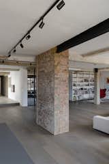 Looking from the kitchen across the living space offers a glimpsed view into the more private areas of the project, while the glass partition enclosing the study reflects a view of the same glazing system on the exterior wall of the original building.