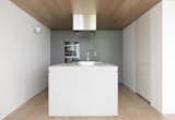 Sandwiched between the timber ceiling and  floor of the first floor, the kitchen is articulated as a series of white volumes of varying heights and proportions.