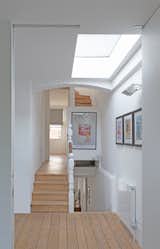 A frameless rooflight on the stair landing provides a horizontal visual cut through the building envelope, reworking the gesture of the vertical glazing in the kitchen below.