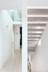 The first-floor hallway is illuminated by pedestrian-loaded glass from the second-floor, which in turn is naturally lit by a large rooflight above. These visual cuts in the floor and roof provide framed views of the sky two floors down into the building. The open-riser staircase brings natural light further down to the deep-plan area of the ground floor.