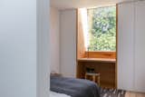 A timber-clad built-in desk forms a window surround to one of the frameless glazed incisions to the building envelope.