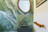 A wall of the ground-floor WC room is clad in striking green stone from floor to ceiling.