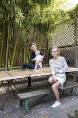 Lara, Ethan, and their baby daughter relax on their back patio, shaded by bamboo.