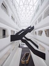 Stark, angular staircases traverse the building’s sleek white interior.