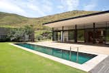Outdoor, Trees, Large Patio, Porch, Deck, Back Yard, Grass, Swimming Pools, Tubs, Shower, and Shrubs The pool stretches across a rolling lawn that ends at the foot of the wooded mountains.  Photos from This South African Villa Lets You Bask in Divine Views