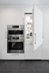 While the cooking appliances remain in the open, the Bosch refrigerator, freezer, and dishwasher are integrated into the cabinetry.